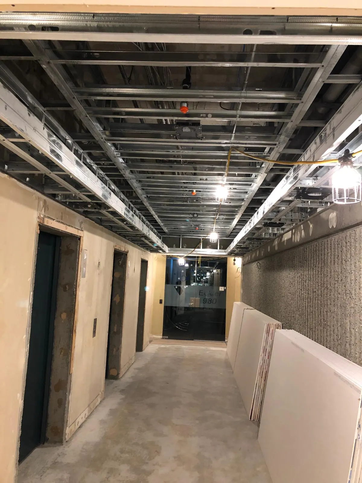 Second angle of the elevator lobby ceiling grid framing, exposed concrete slab and rough-in wiring above