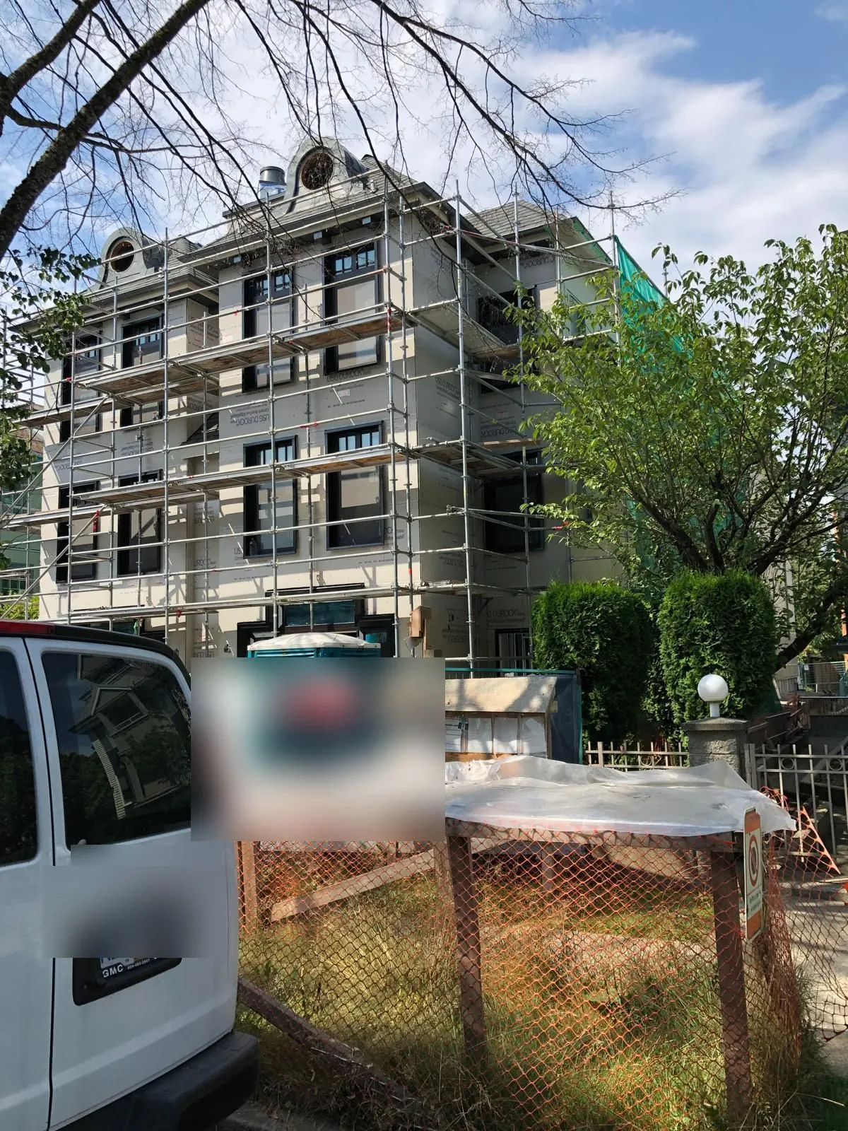 Exterior of the building wrapped in scaffolding during the renovation, decorative dormer windows visible at the roofline