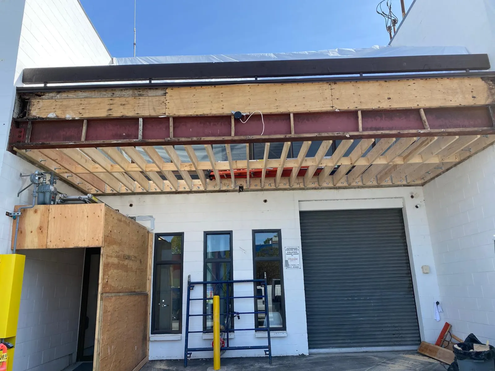 Structural steel beam and new timber roof joists tying into an existing building over a loading entrance, exterior view