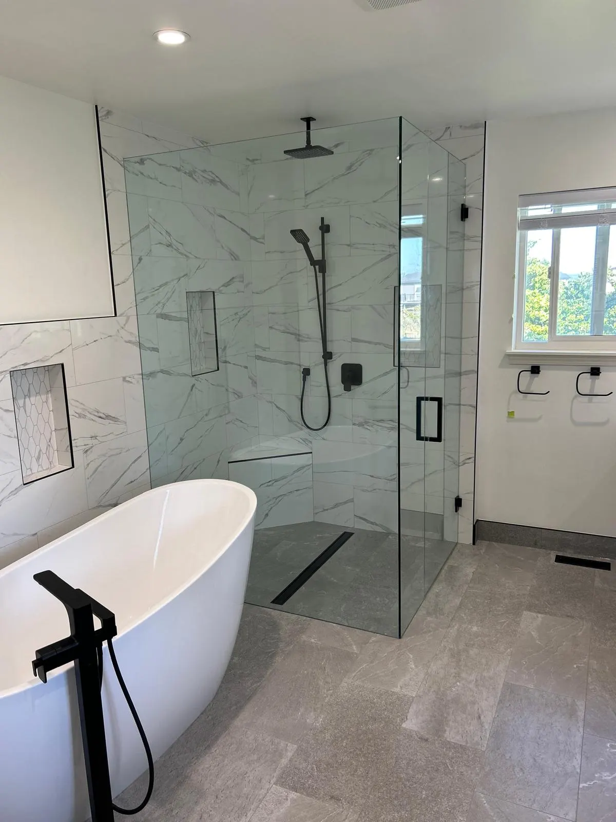Finished bathroom with a freestanding soaker tub and marble tile shower