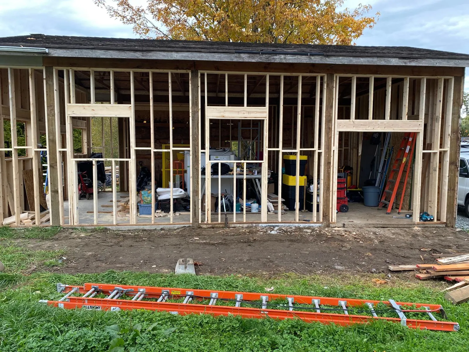 Front view of the finished cabin with a stacked firewood pile and covered entry
