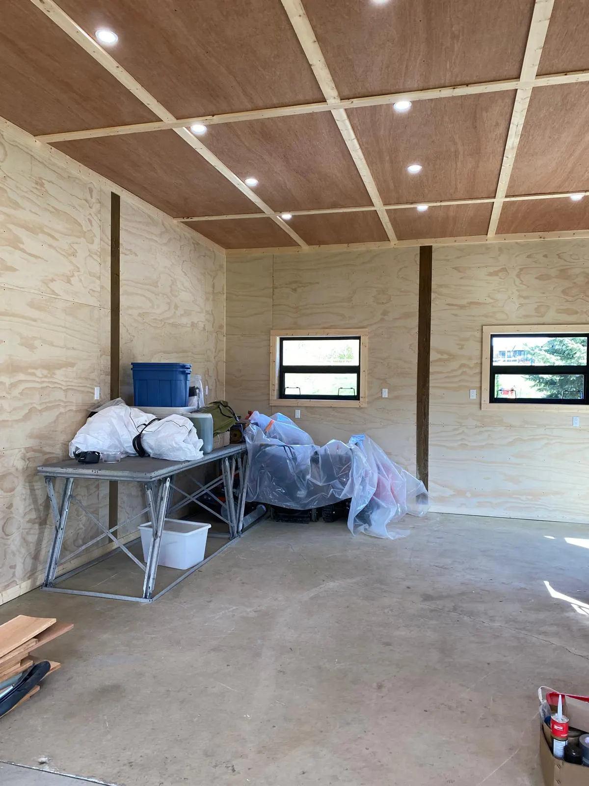 Interior of the cabin with a finished plywood ceiling and walls, storage table, and windows
