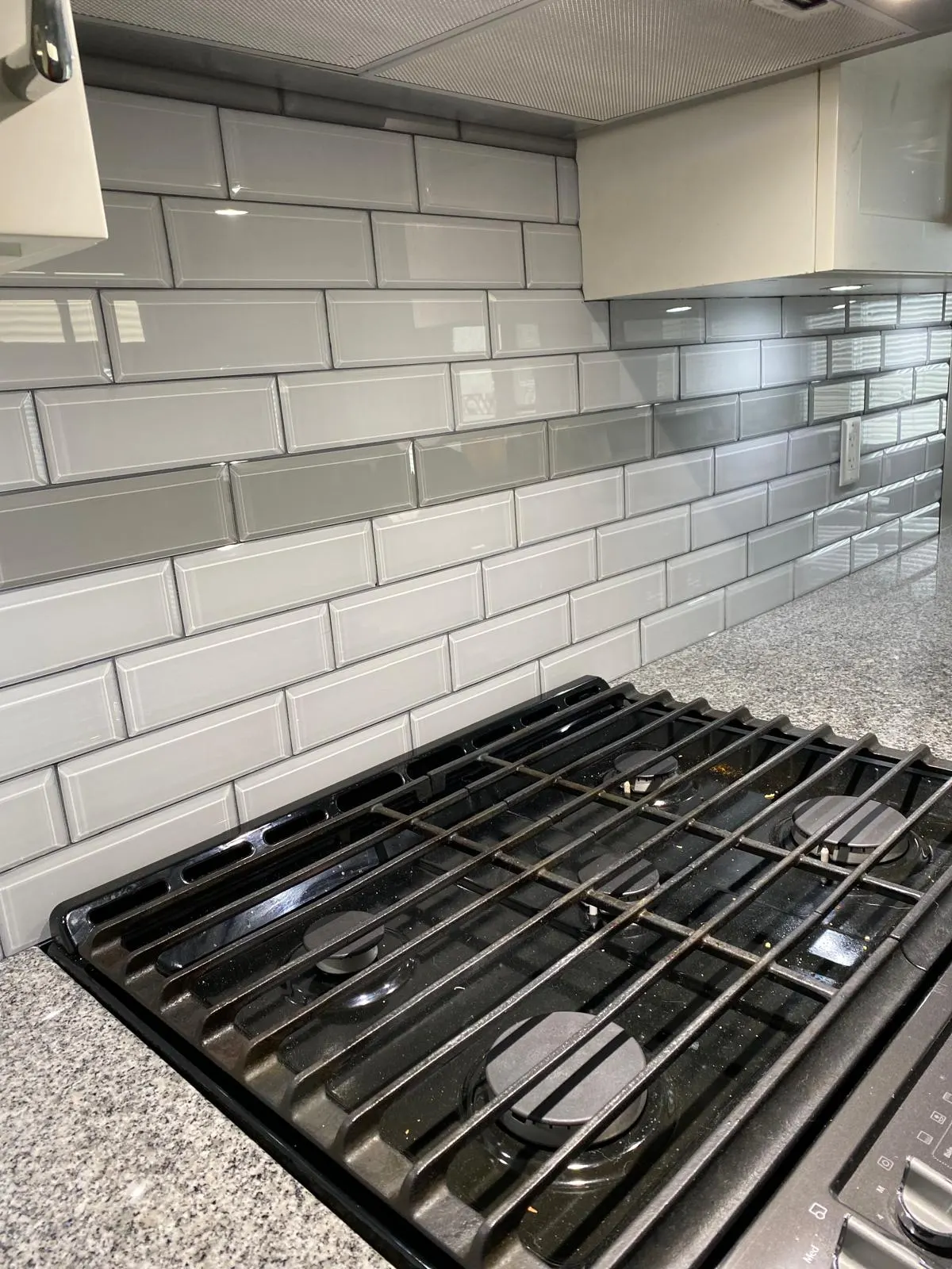 Close-up detail of a finished stone backsplash and quartz countertop in a residential kitchen