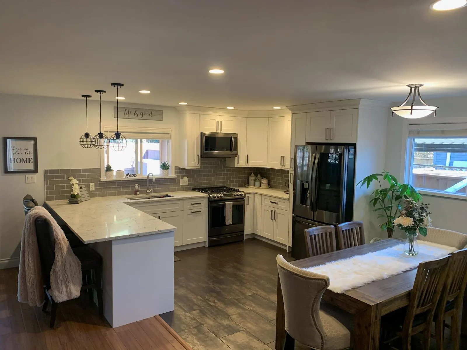 Open-concept kitchen with grey subway tile backsplash, black stainless appliances, and an adjoining dining area